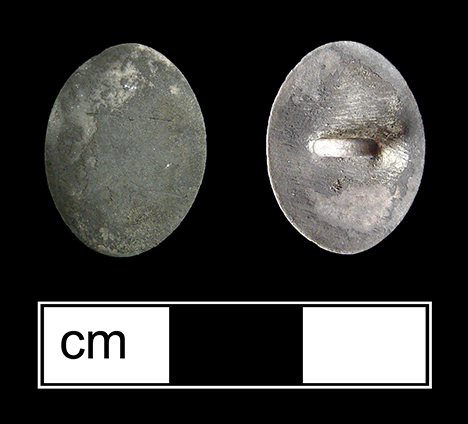 White metal oval link, possibly silver. There is no evidence of decoration, but the link has been burned and is covered in soot.
